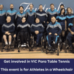 Group photo of wheelchair athletes in matching blue and gray uniforms, posing in a gym for a wheelchair table tennis team event.